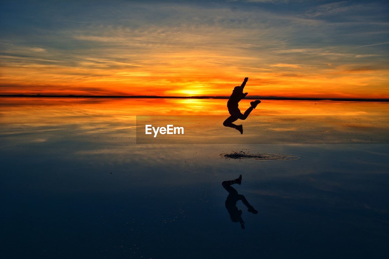 Silhouette man jumping at salar de uyuni during sky