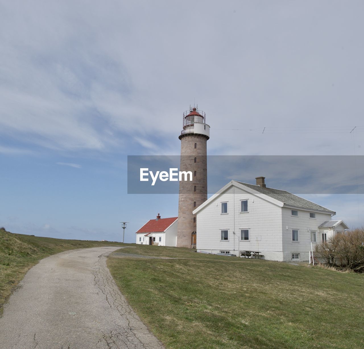 Lighthouse on field against sky