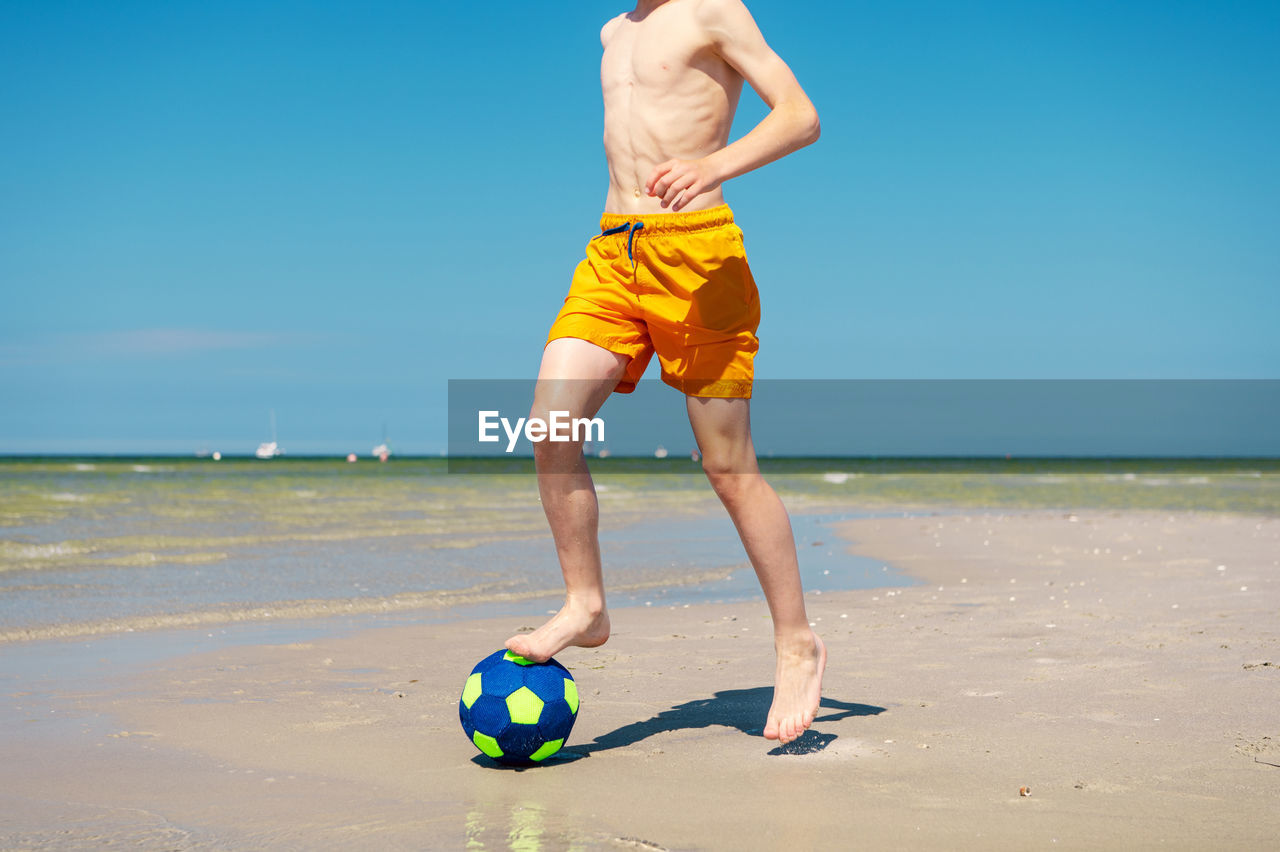 MAN WITH BALL ON BEACH