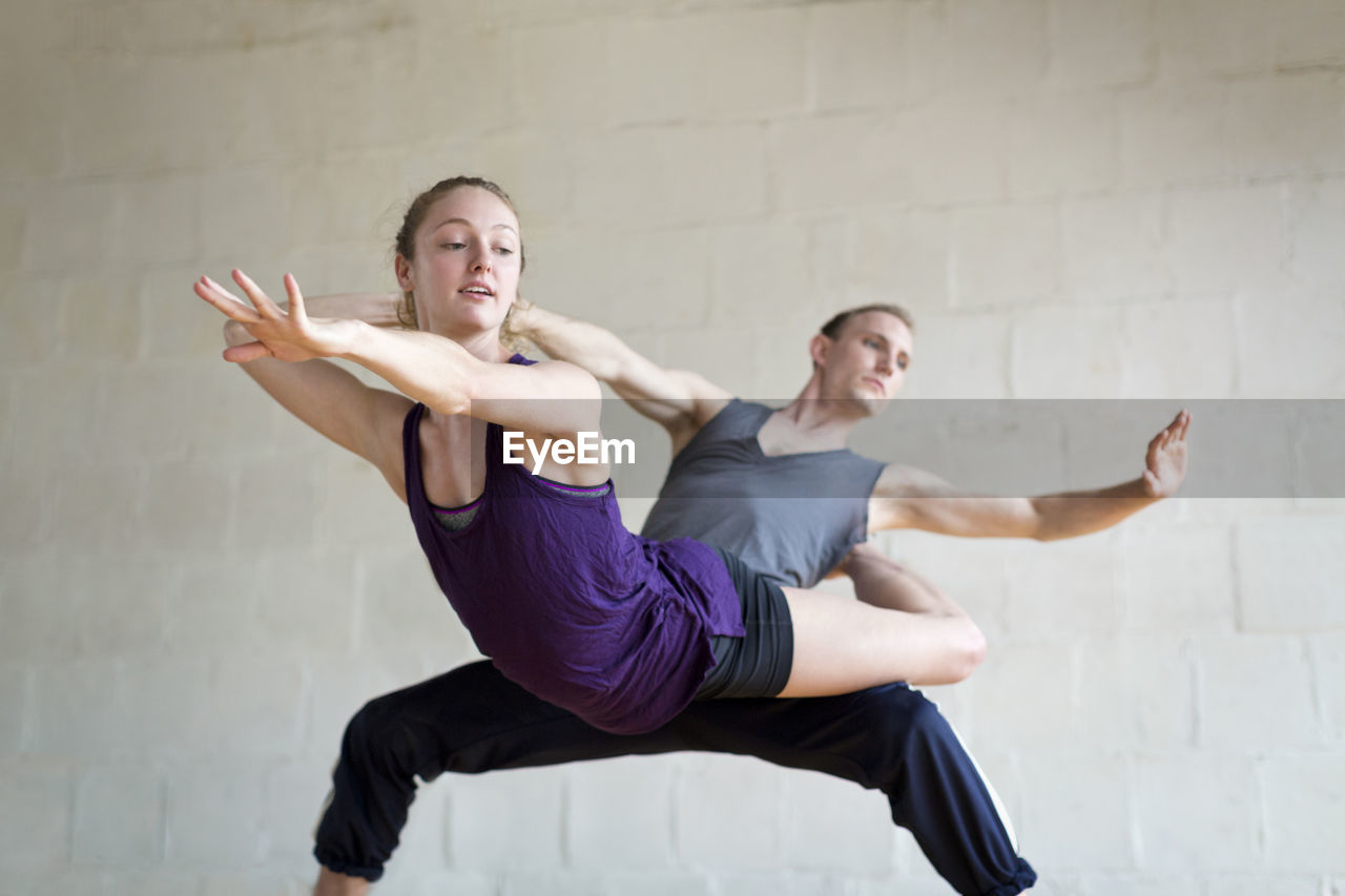 Ballet dancers practicing against wall in studio