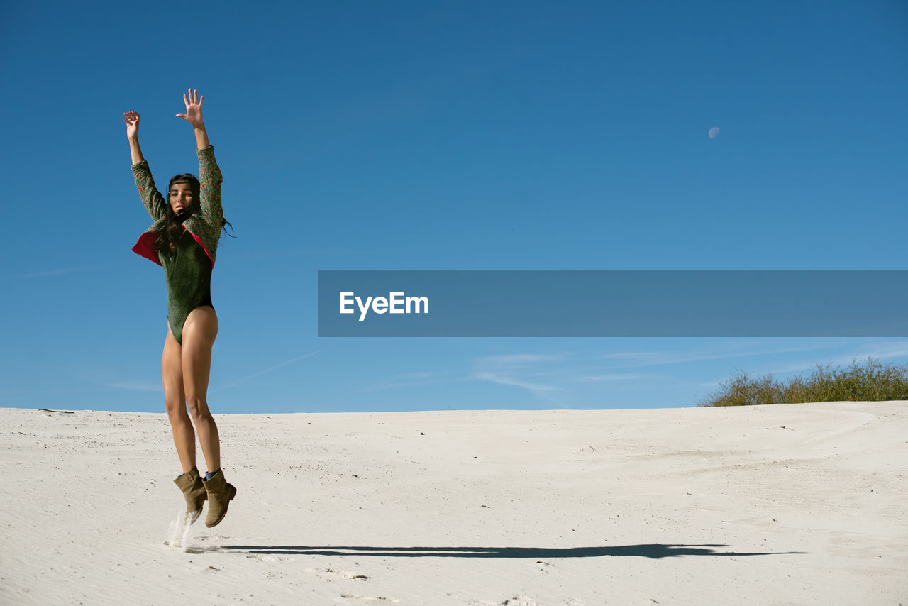 Woman standing on beach against blue sky