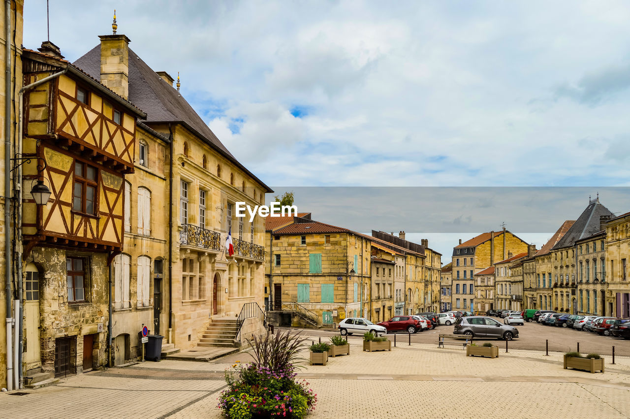 Houses by street amidst buildings against sky