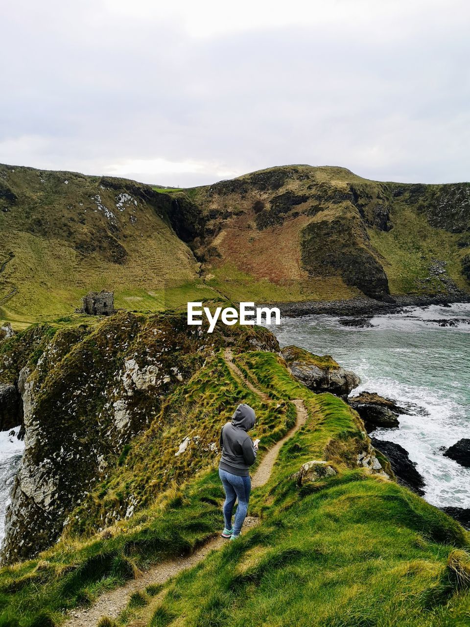 Rear view of woman standing on mountain by sea