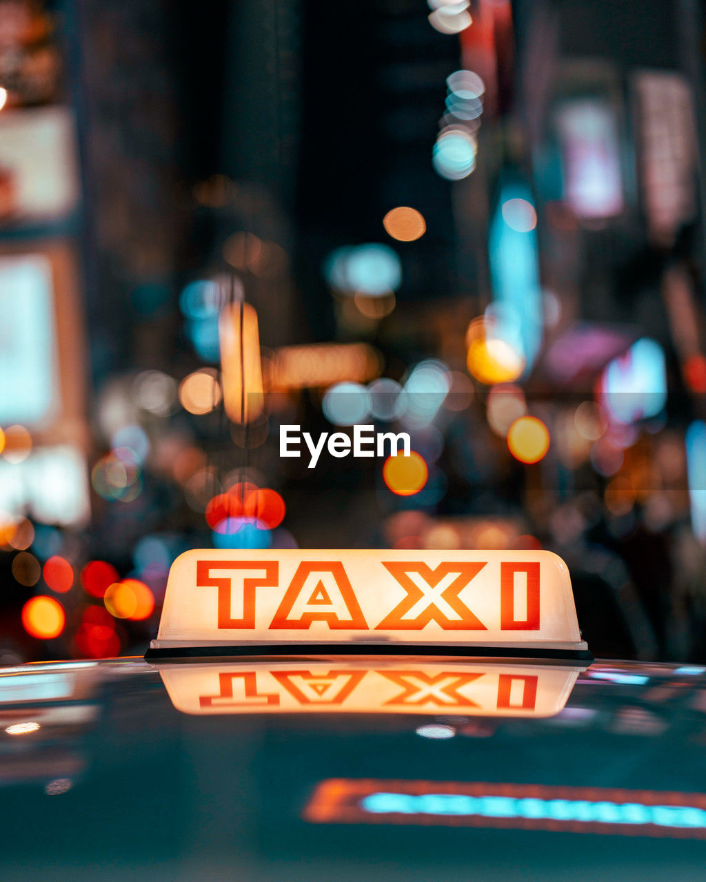 Close-up of illuminated taxi signbox with bokeh of city night
