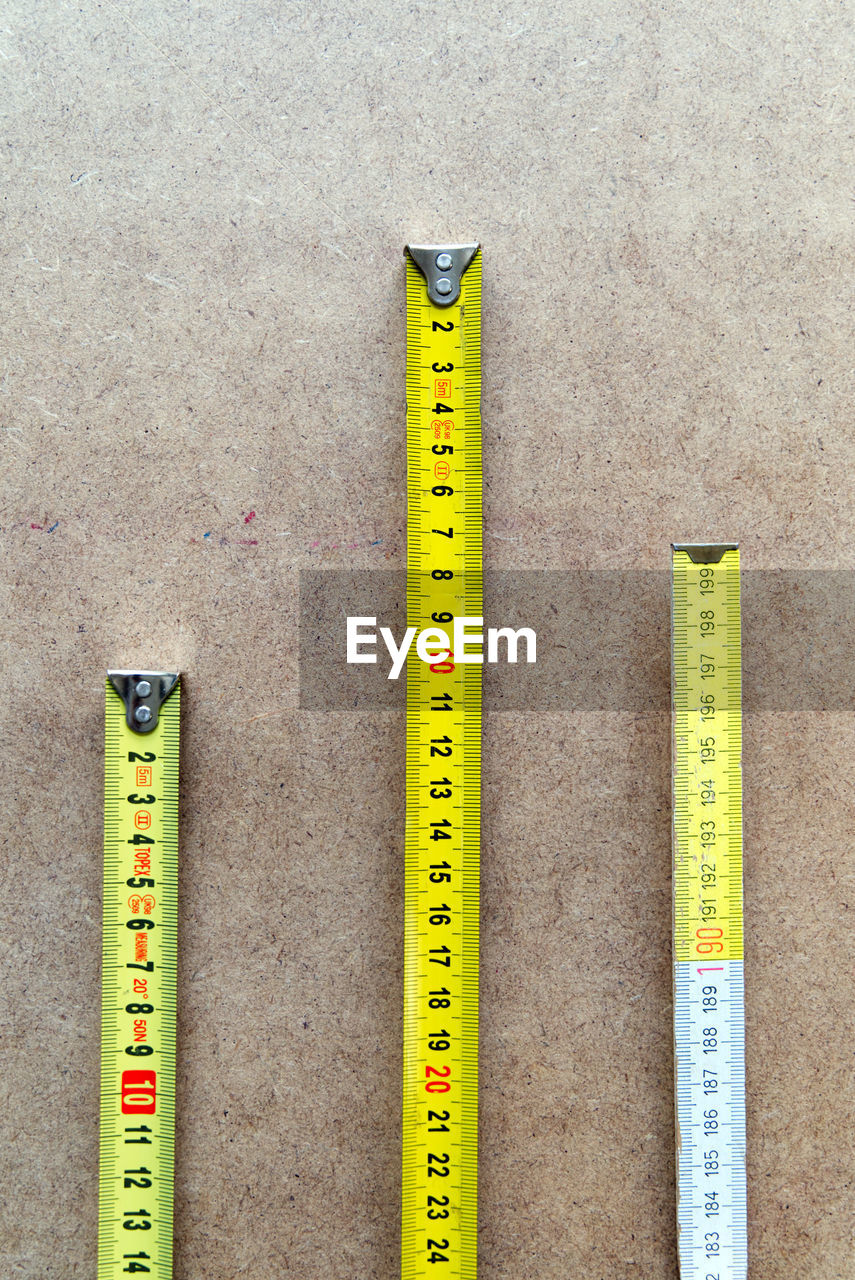 yellow, ruler, instrument of measurement, tape measure, number, no people, measuring, high angle view, still life, accuracy, indoors, close-up, directly above, tool