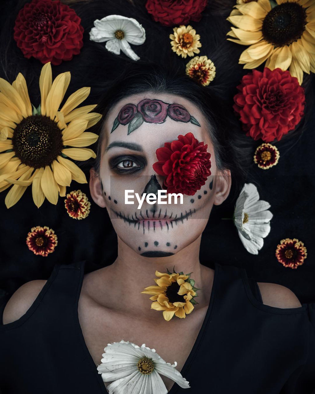 Directly above portrait of woman with halloween make-up lying amidst flowers