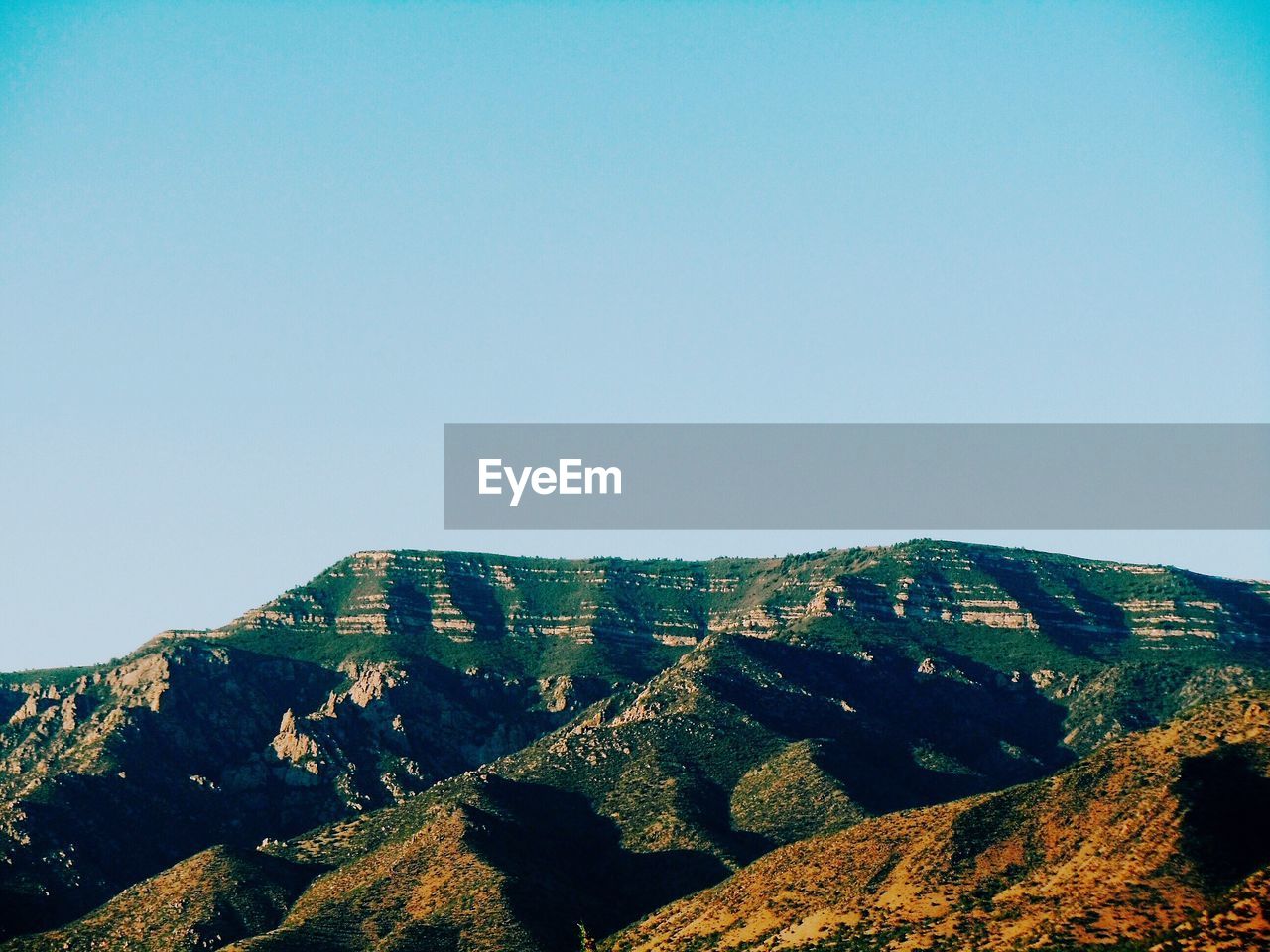 Scenic view of mountain against clear blue sky