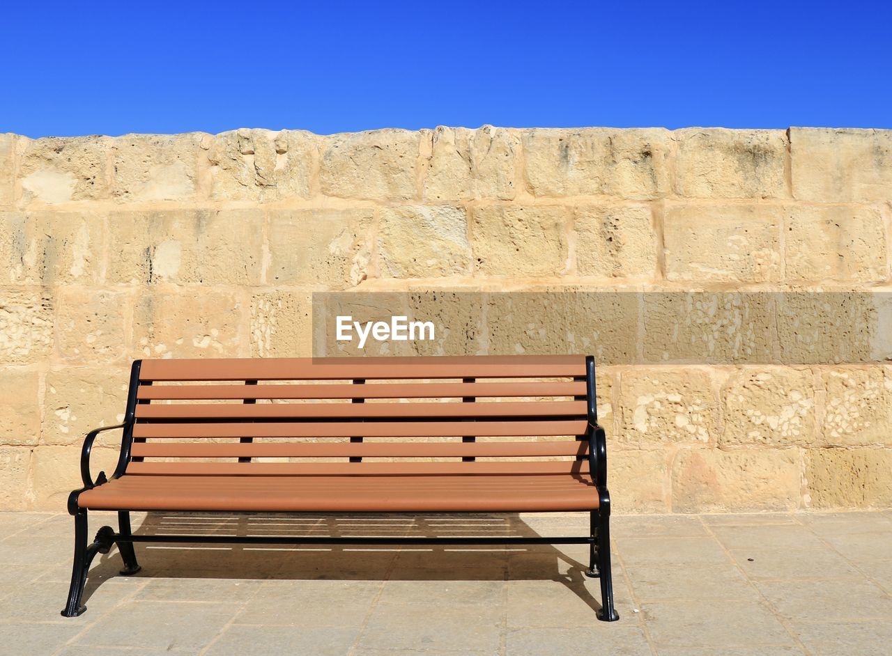 EMPTY BENCH AGAINST BLUE WALL