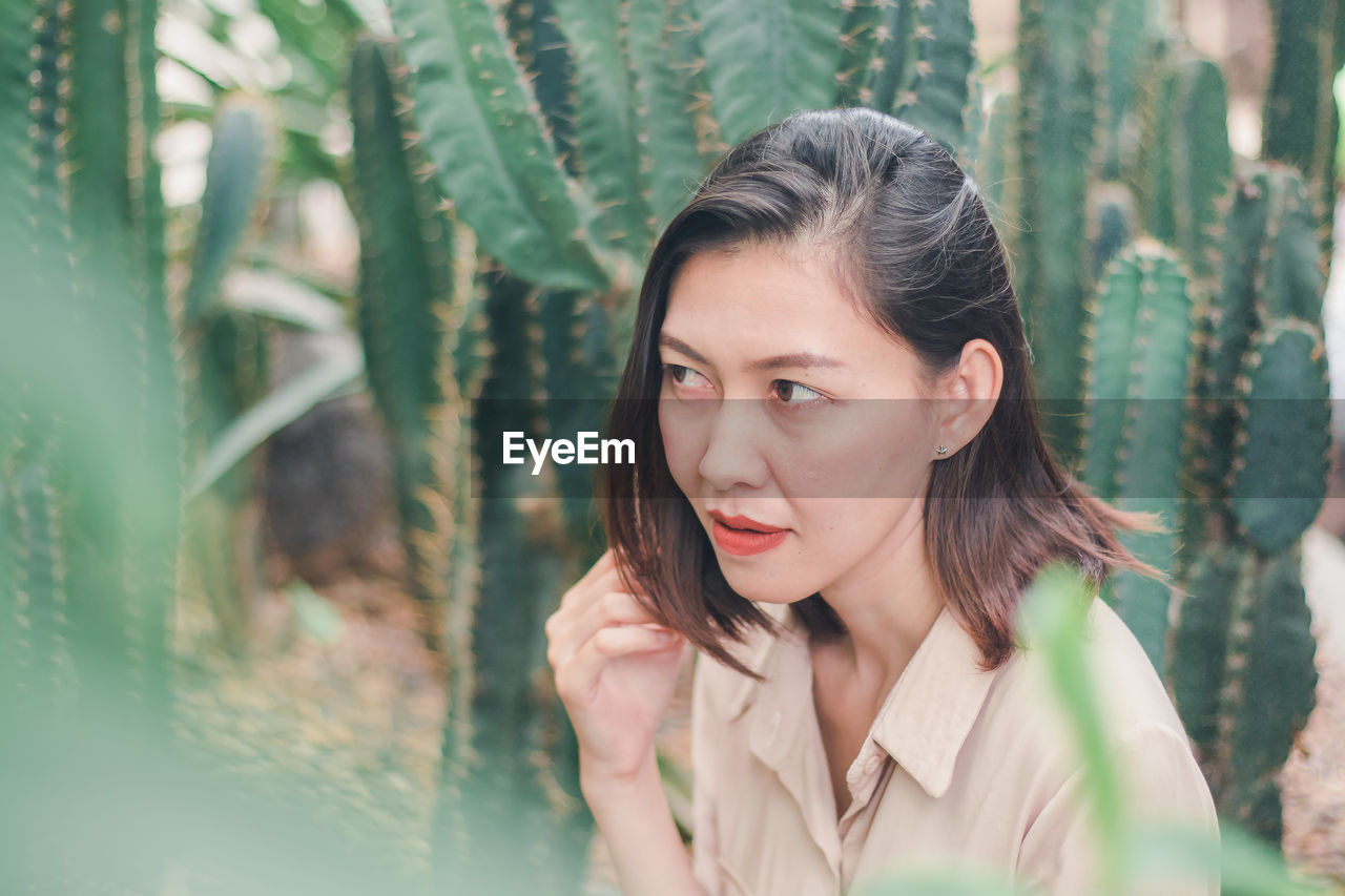 Woman looking away against cactus