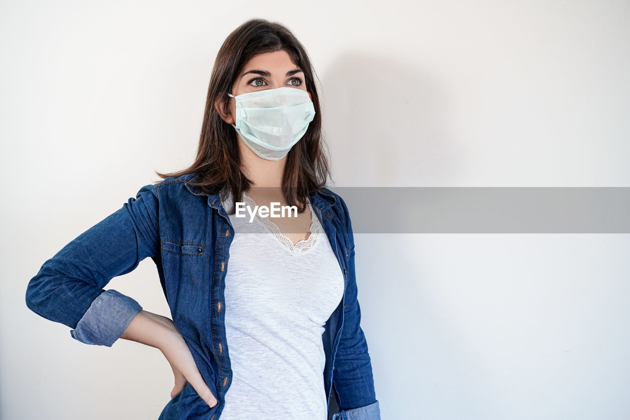 PORTRAIT OF WOMAN STANDING AGAINST WHITE BACKGROUND