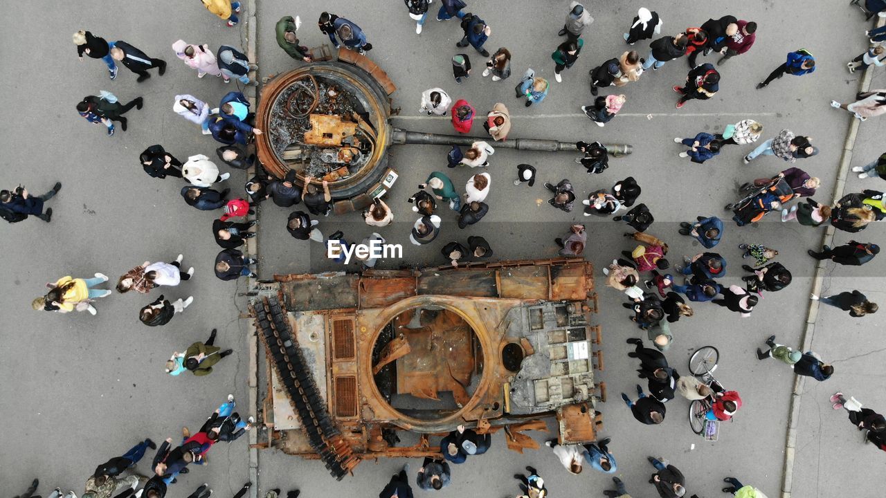 High angle view of people walking on street next to the wrecked russian fascist equipment