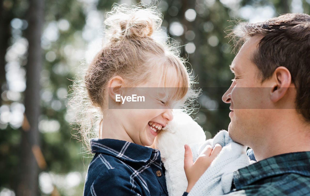 Little girl laughing with her daddy carrying her smiling at her