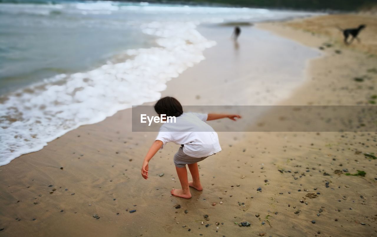 REAR VIEW OF BOY WALKING ON SHORE