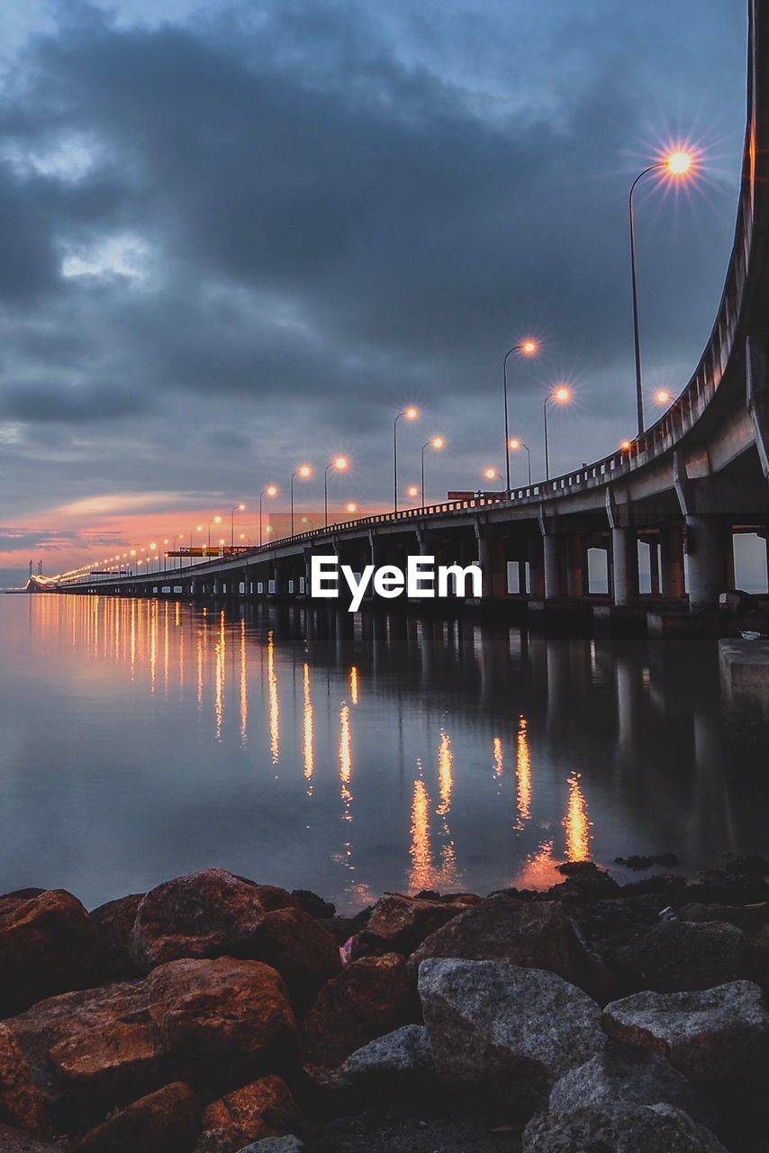 Illuminated bridge over river against sky