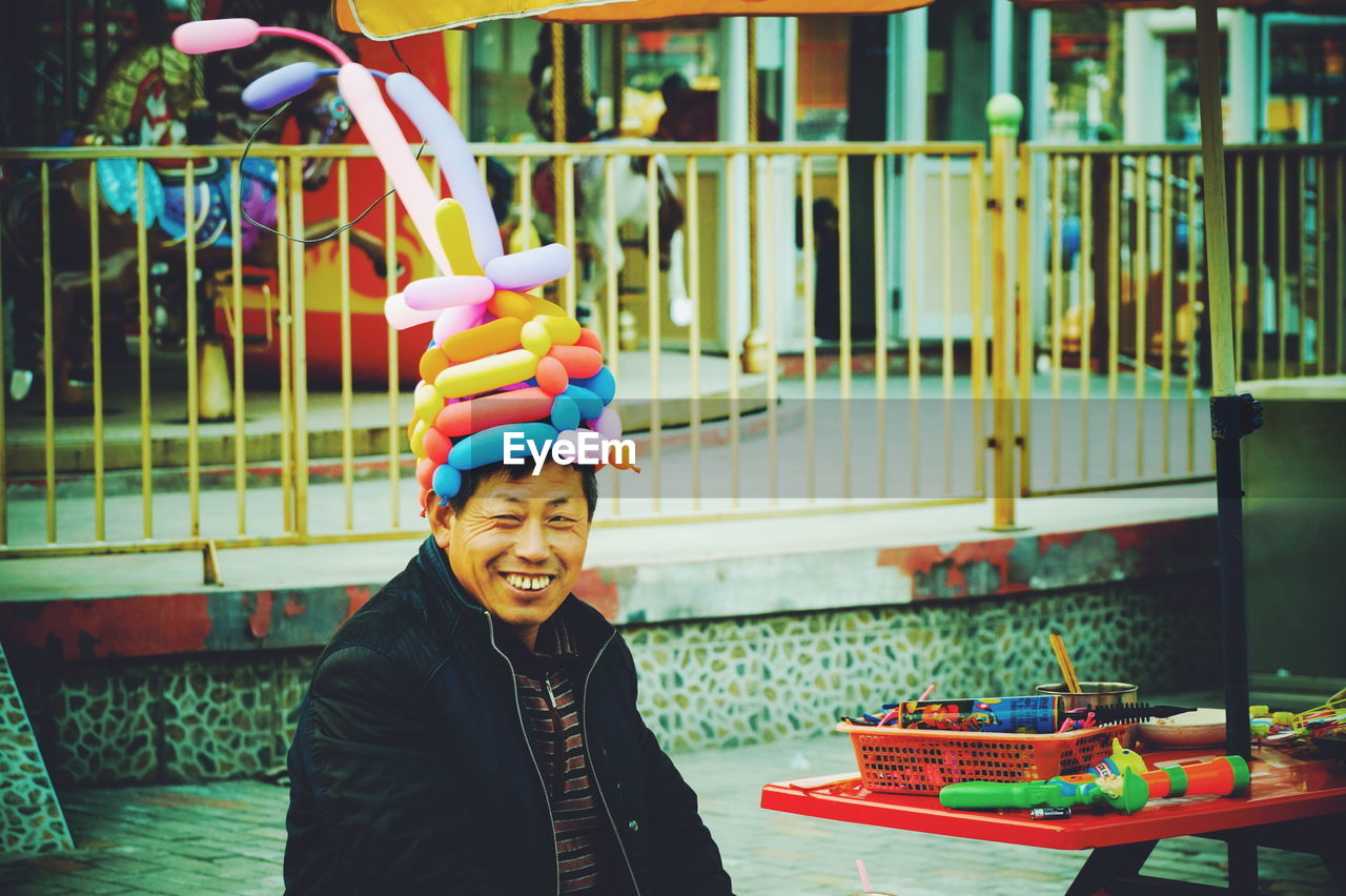 Happy man wearing balloon hat in amusement park
