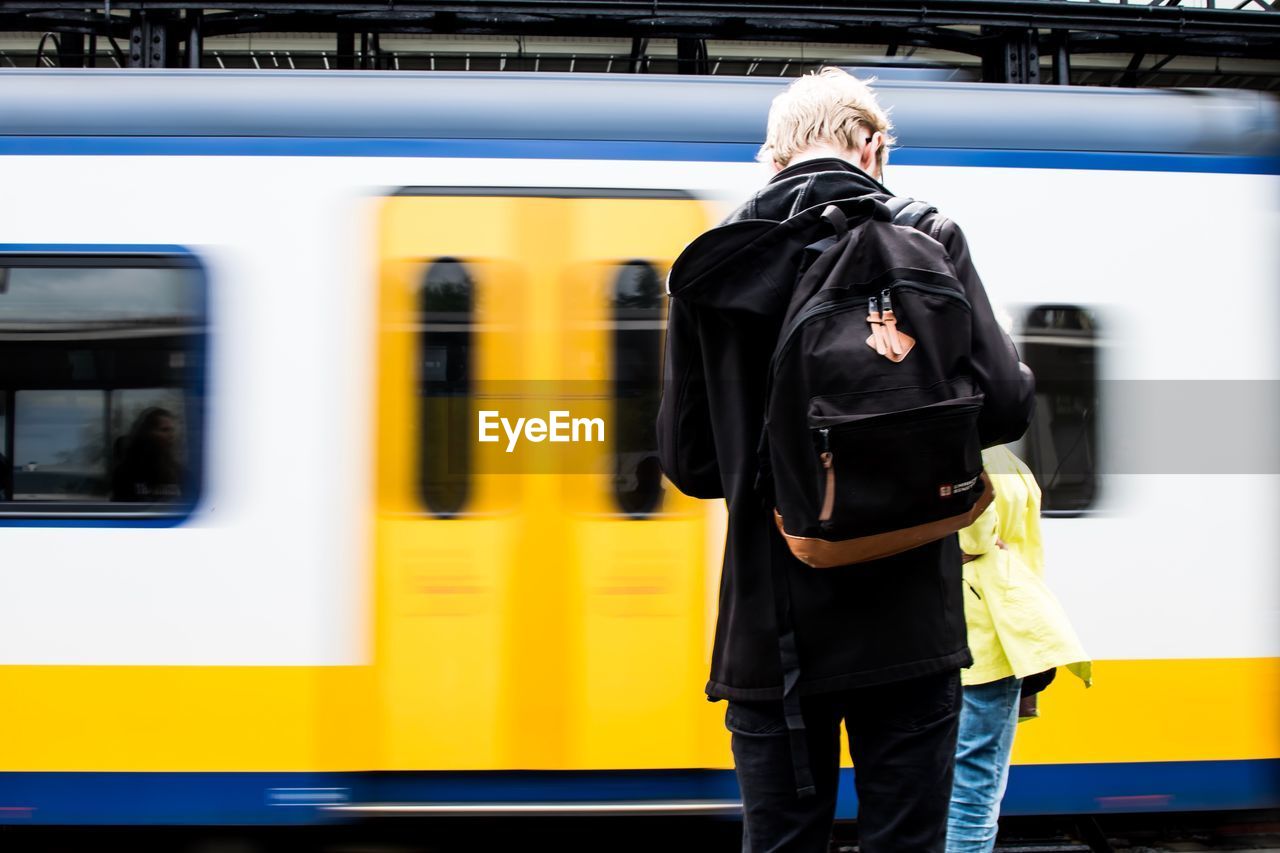 Rear view of men standing by train at railroad station platform