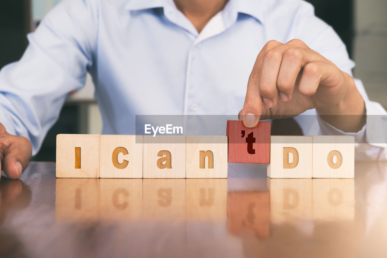 Midsection of businessman with text on toy blocks at desk