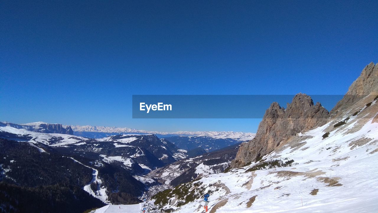 Scenic view of snowcapped mountains against clear blue sky