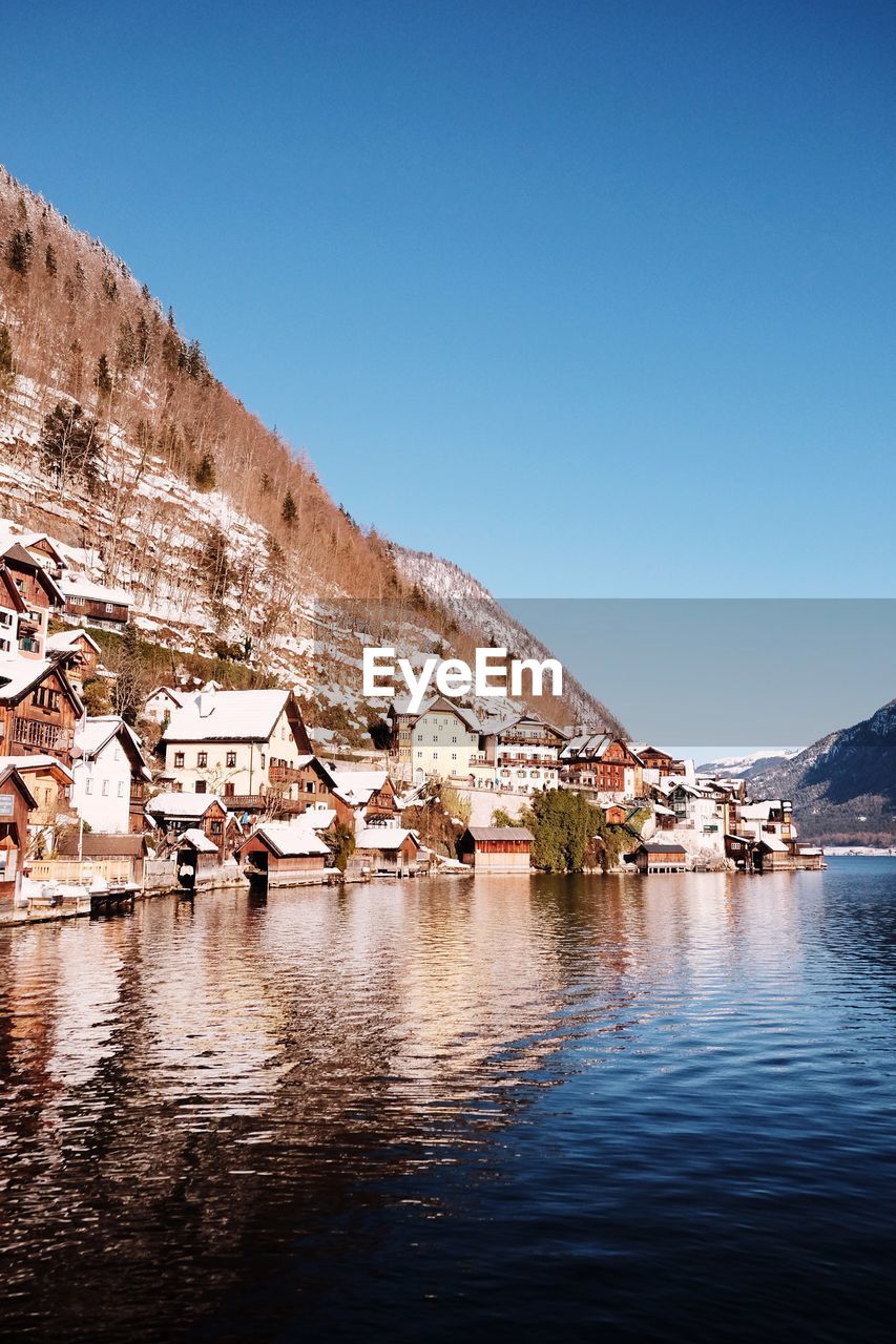 HOUSES BY LAKE AGAINST CLEAR SKY