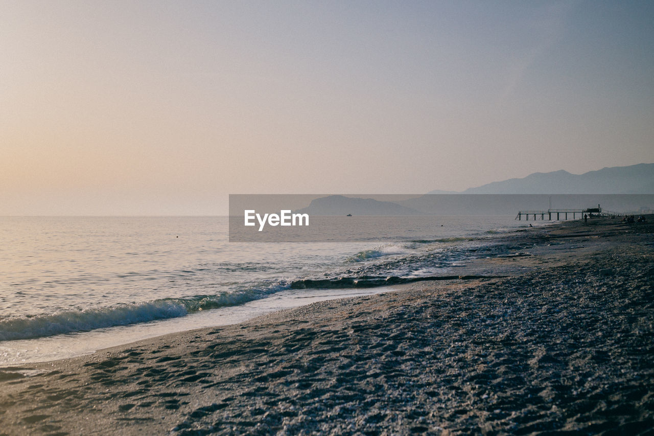 Scenic view of beach against clear sky during sunset