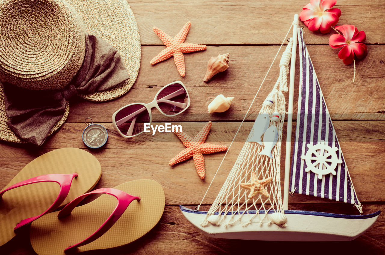 High angle view of personal accessories with navigational compass and boat on wooden table