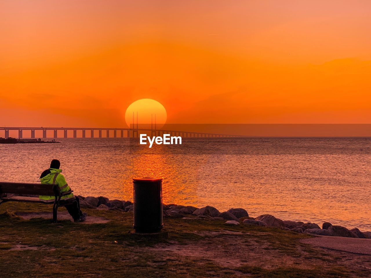 Man looking at sea against orange sky