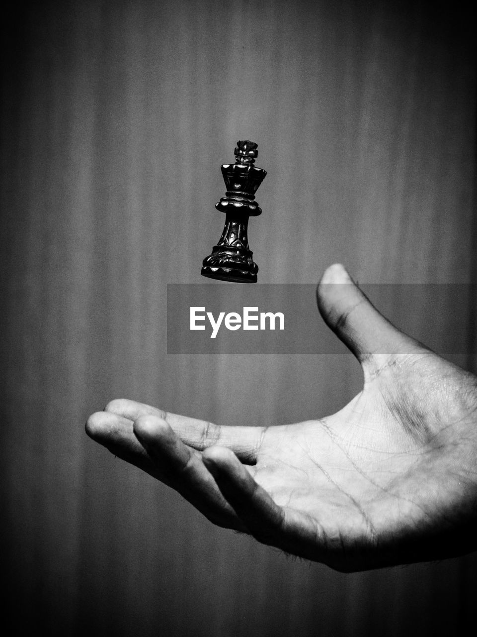 Close-up of hand catching chess piece against wall