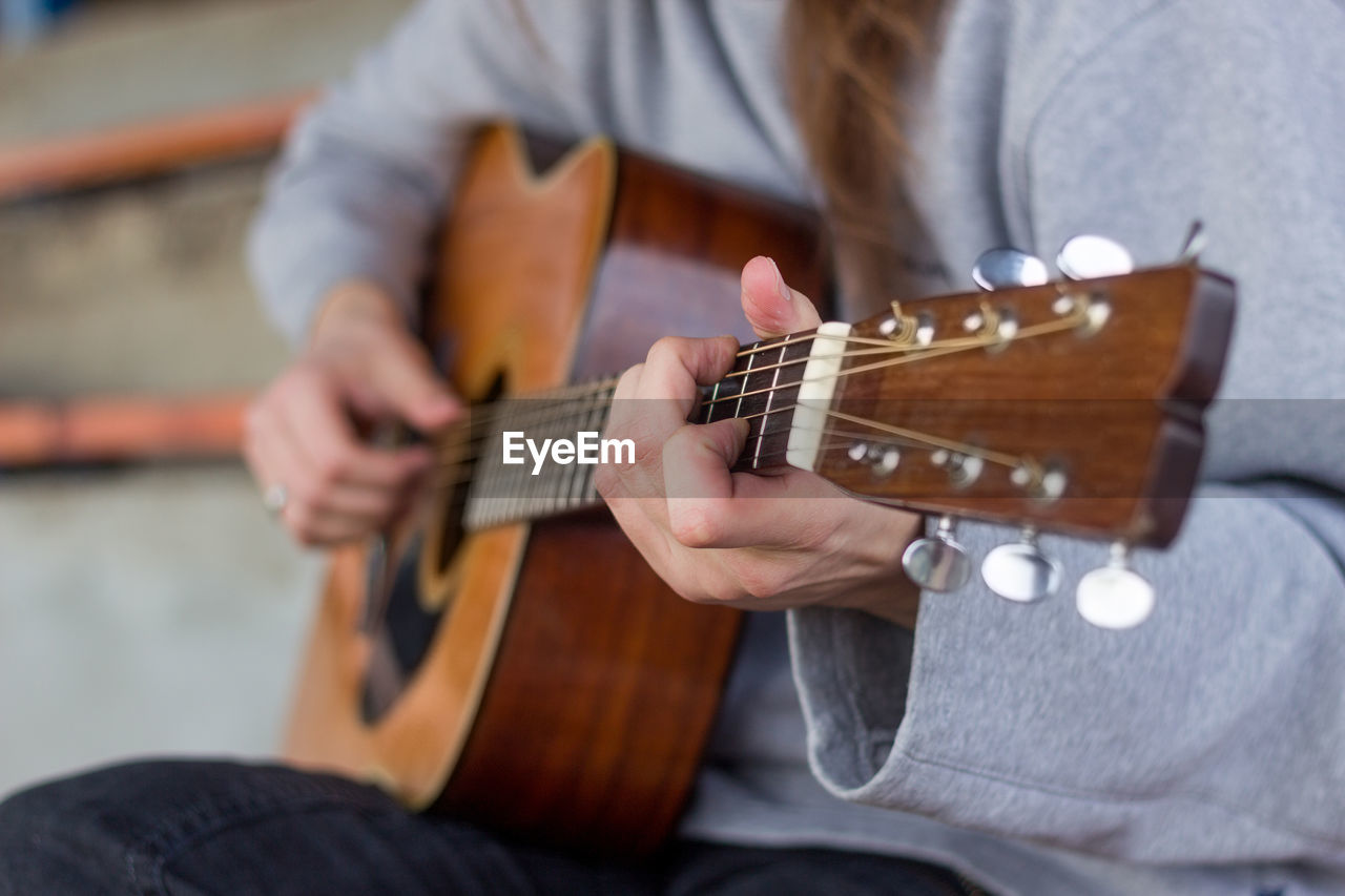 Midsection of woman playing guitar outdoors