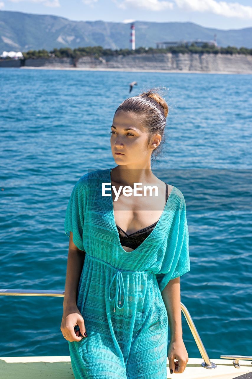 Young woman looking away while standing in boat at sea