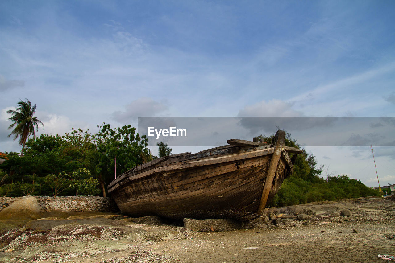 Abandoned boat on shore against sky