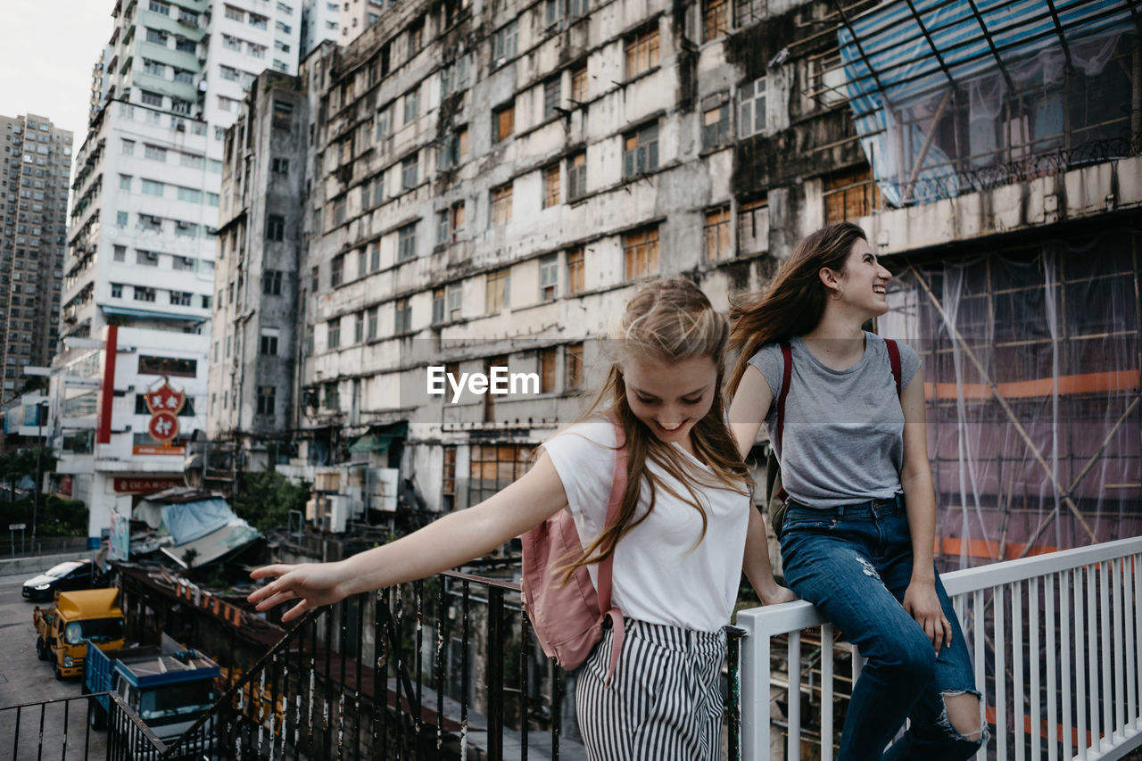 Smiling female friends against buildings in city