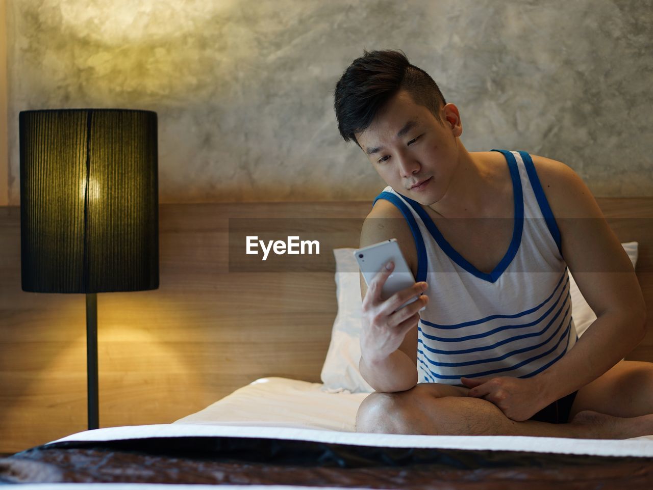 Man using mobile phone while sitting on bed