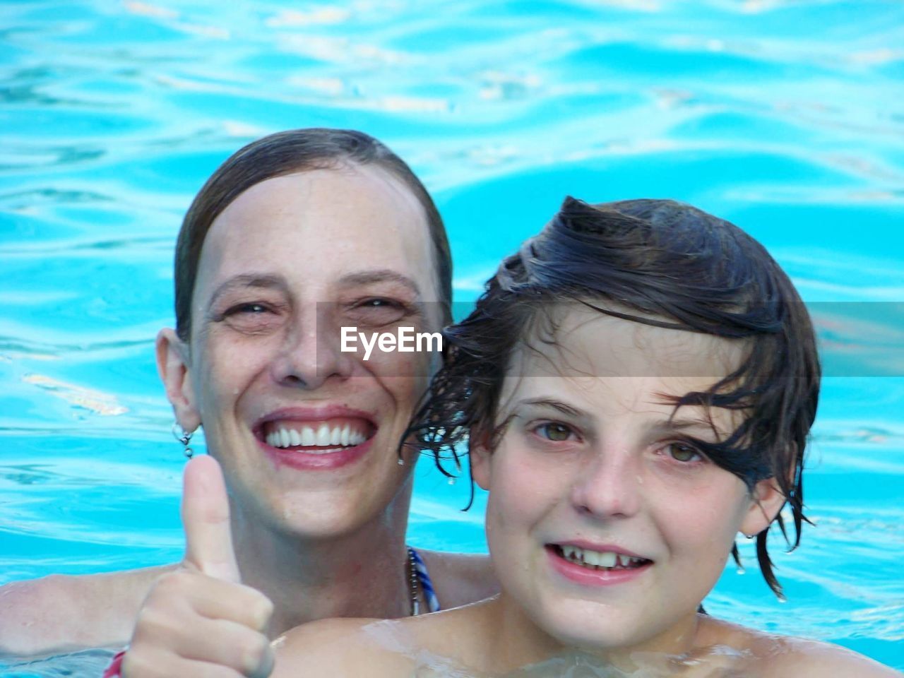 Close-up portrait of smiling mother and son in swimming pool