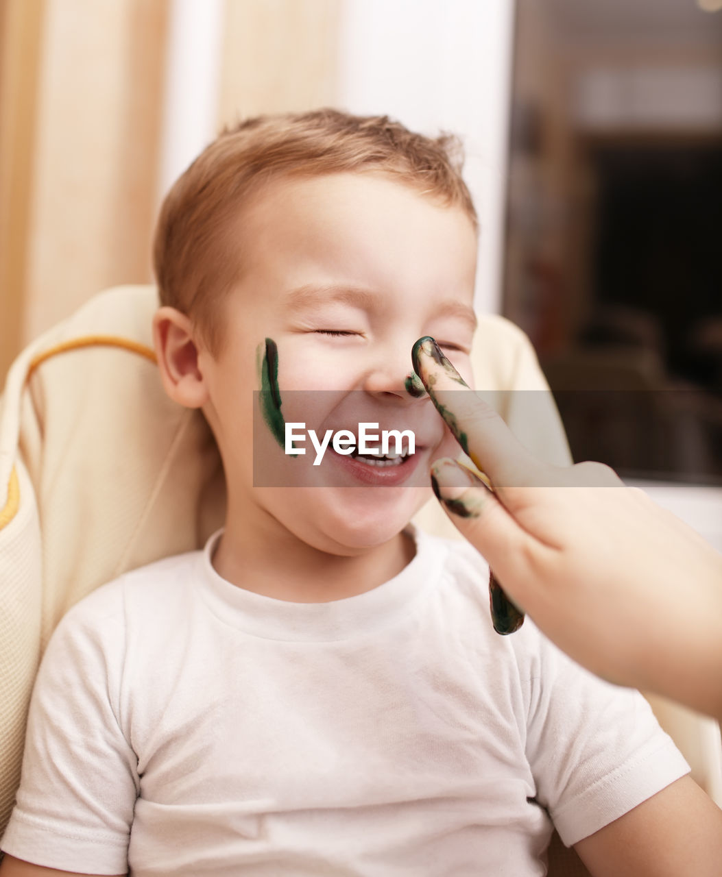 Cropped hand of woman painting boy face