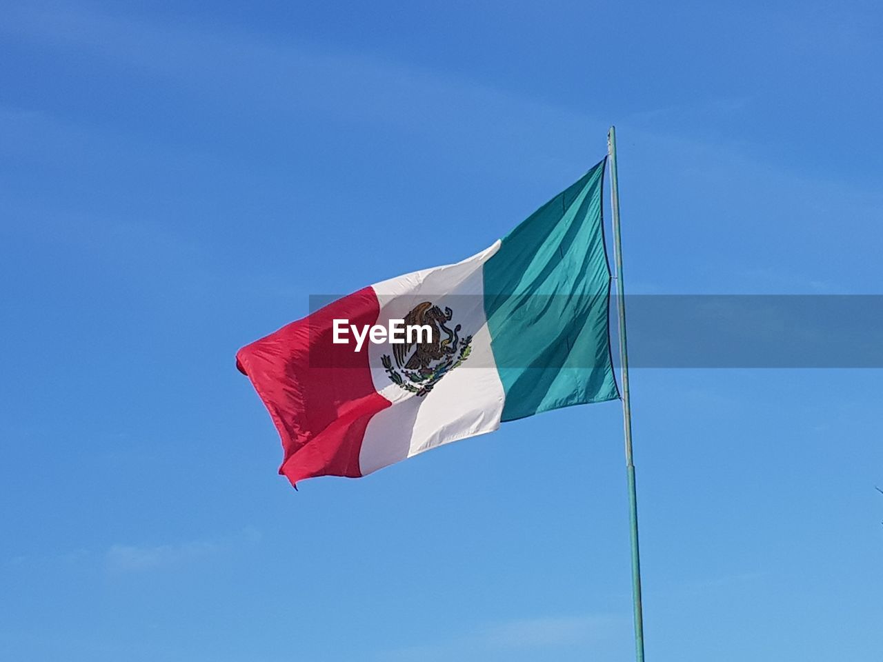Low angle view of mexican flag against blue sky