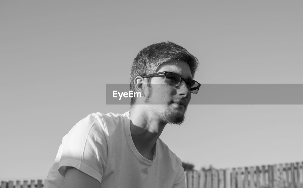 Young man wearing sunglasses while sitting outdoors