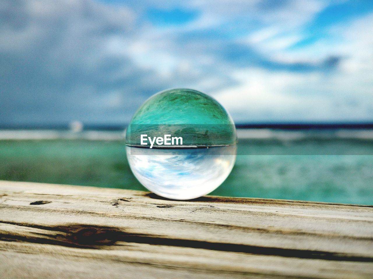 Close-up of crystal ball on sea against sky