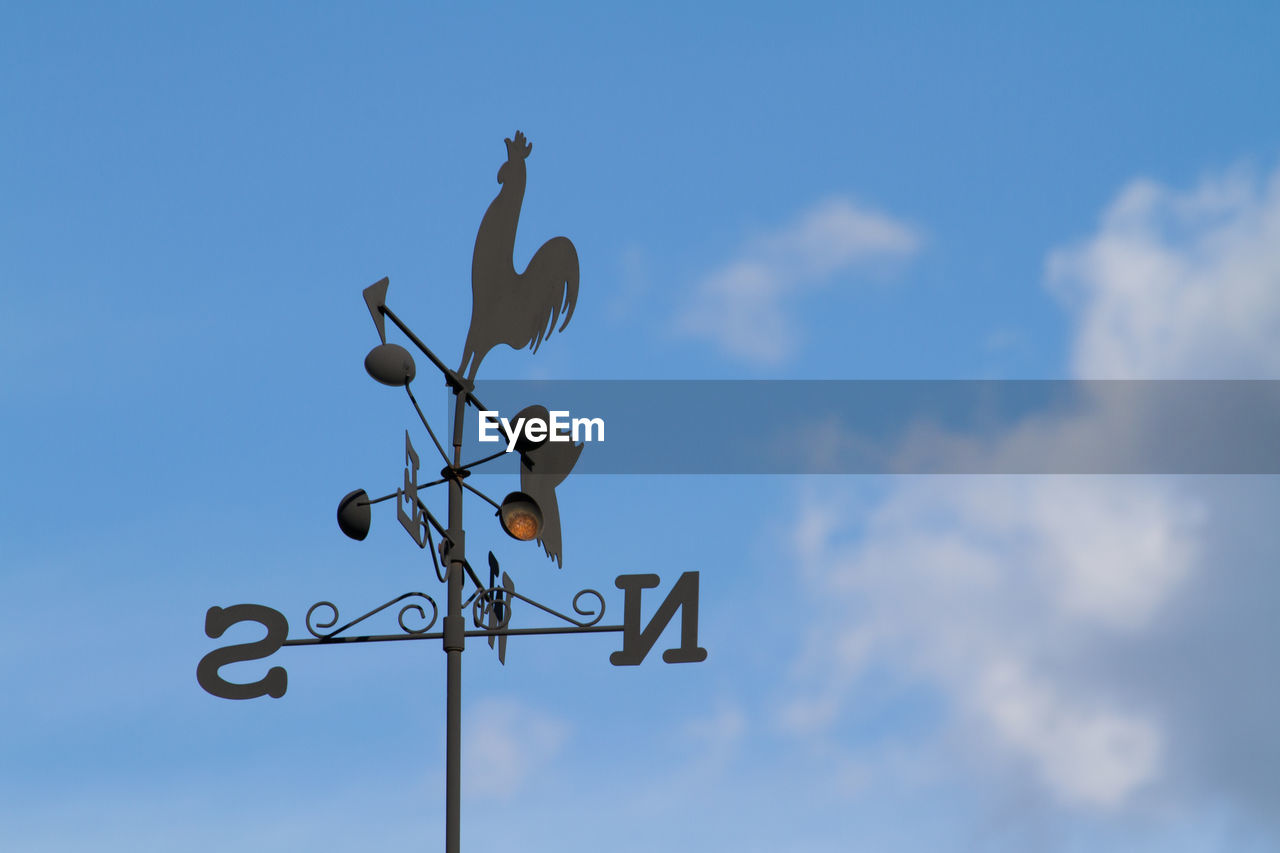 Low angle view of weather vane against blue sky