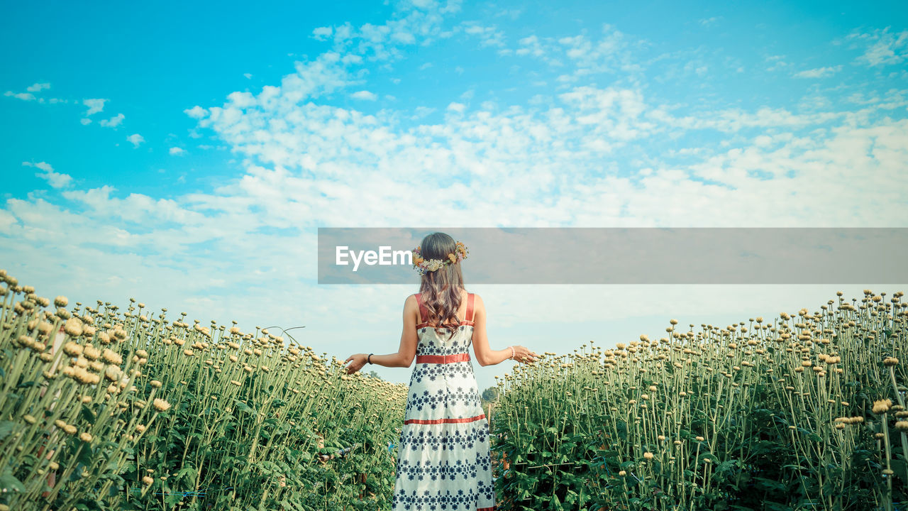 Woman standing on field against sky