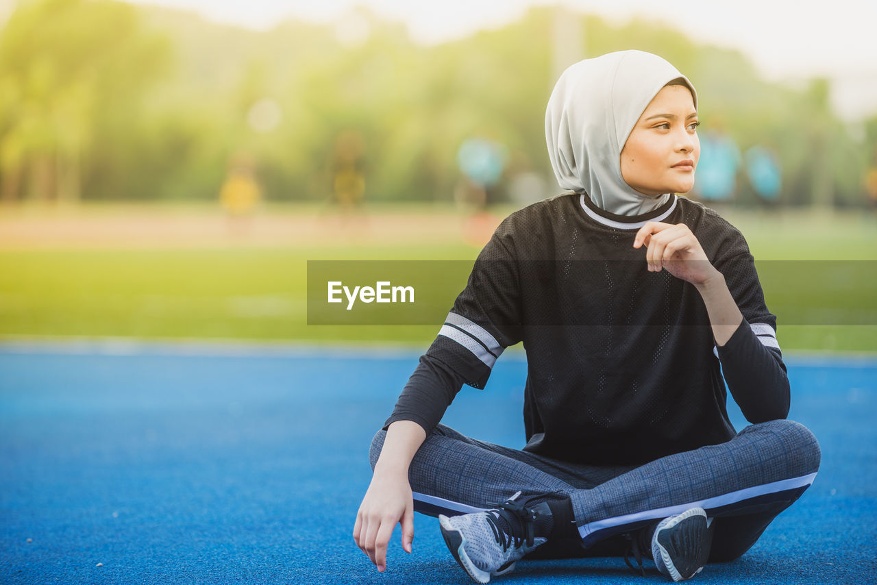 Thoughtful female athlete sitting at stadium