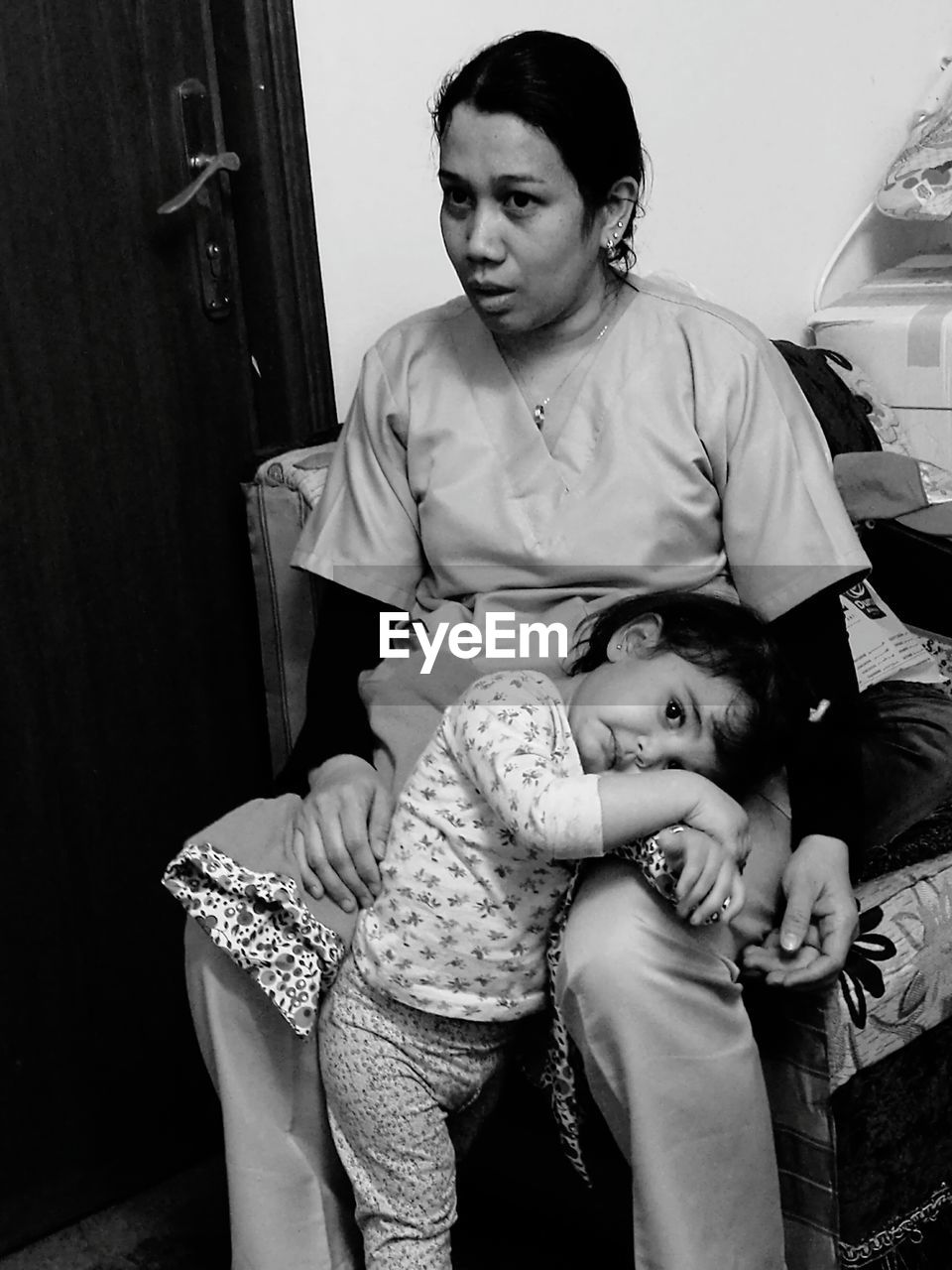 Mother sitting with daughter on chair at home