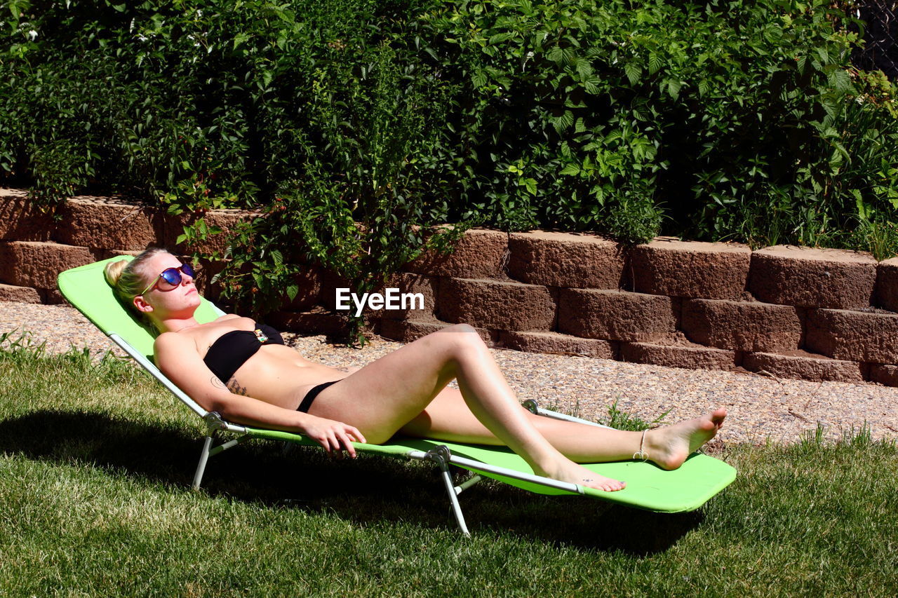 Woman in bikini lying on lounge chair