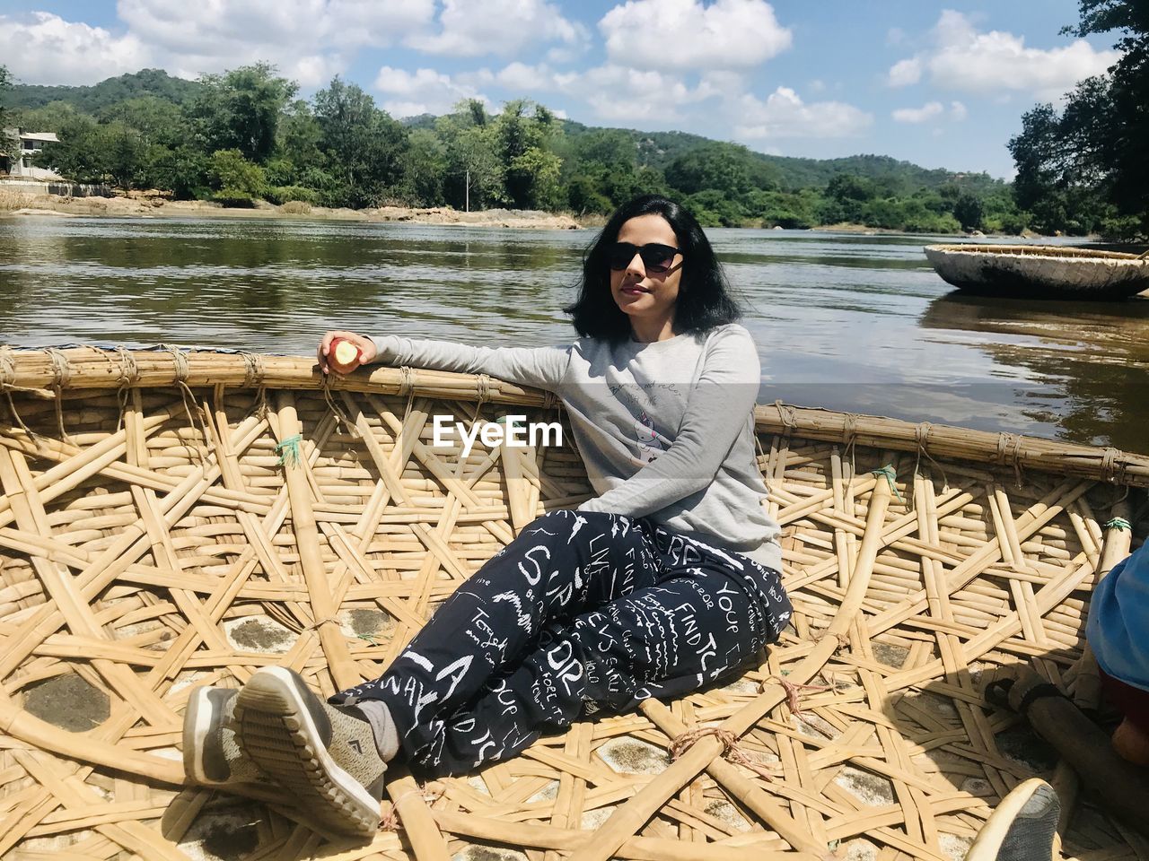 Portrait of woman wearing sunglasses sitting in boat on lake