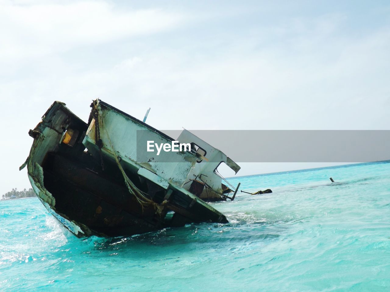 Damaged boats in sea against sky
