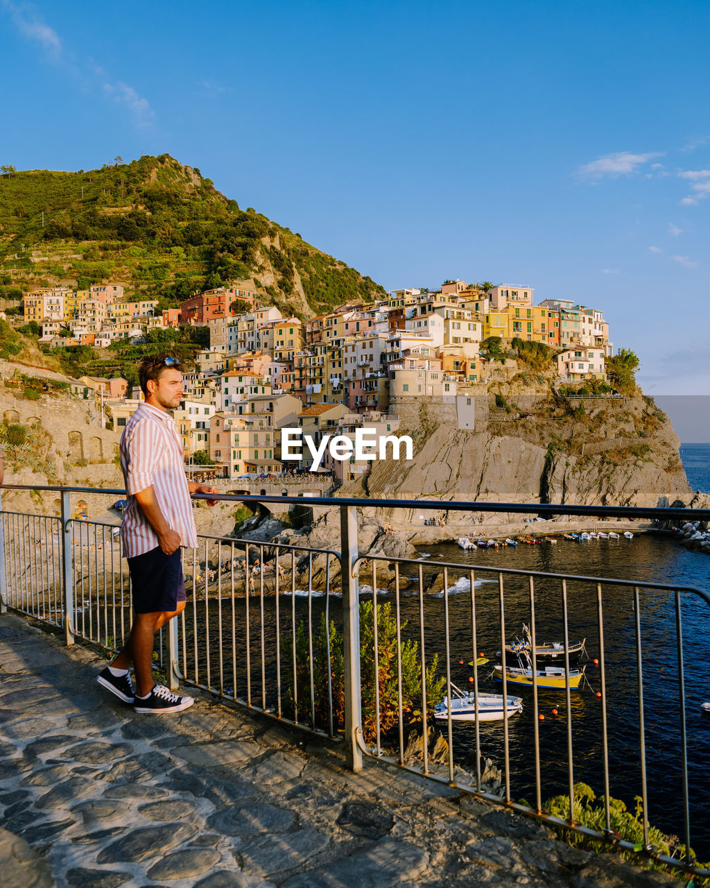 MAN STANDING BY RAILING AGAINST BUILDING