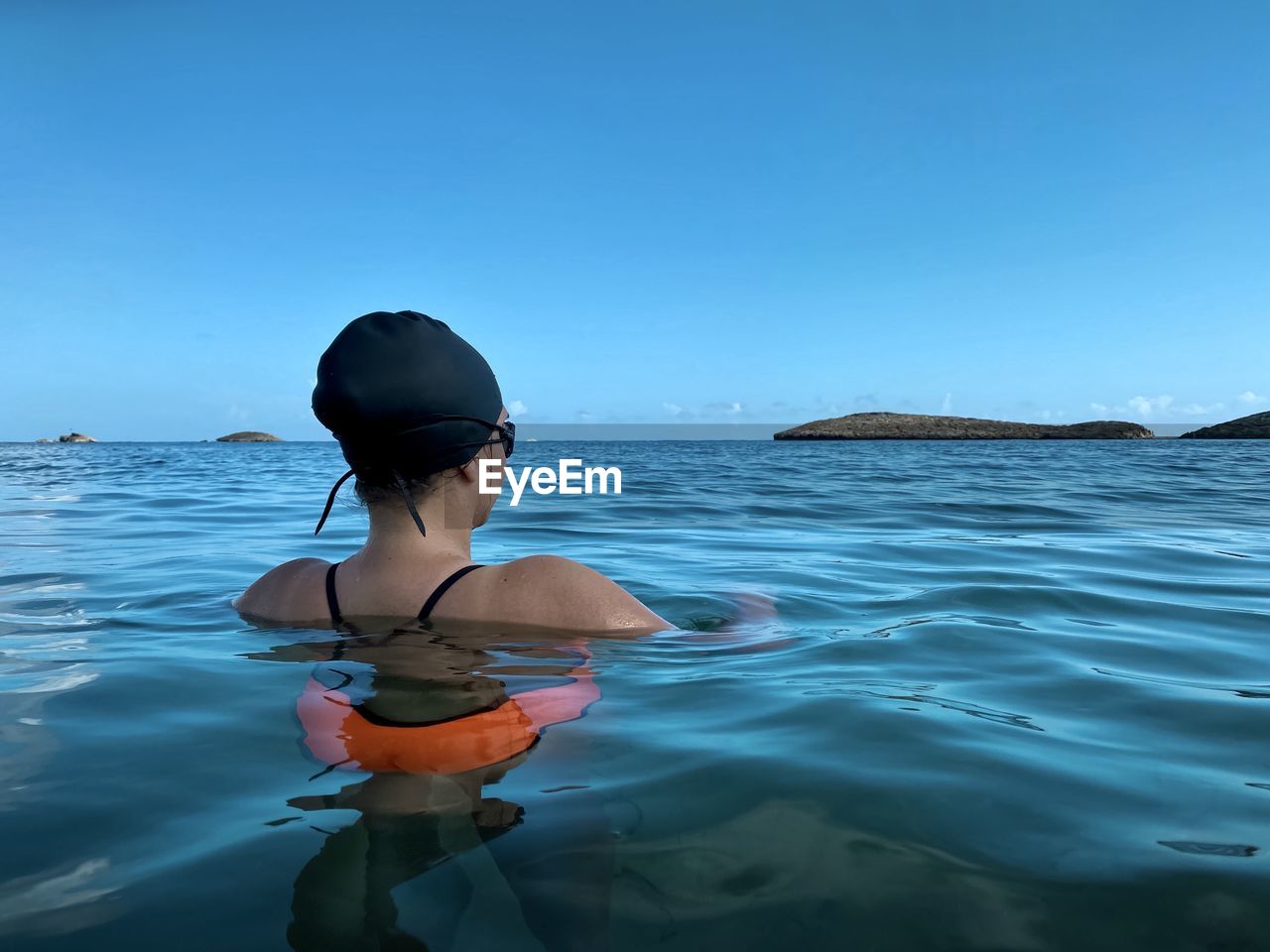 Rear view of woman in sea against clear blue sky