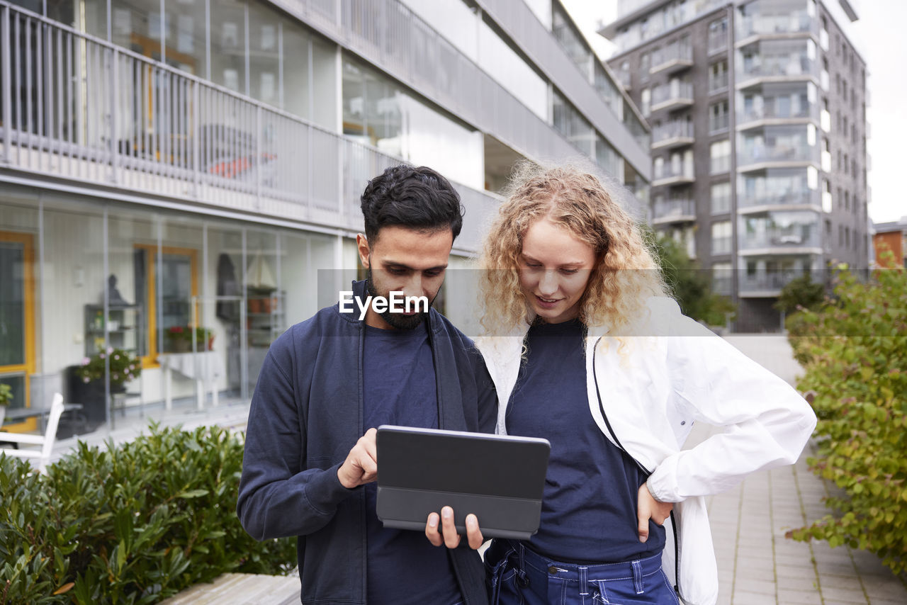 Male and female worker looking at tablet in courtyard
