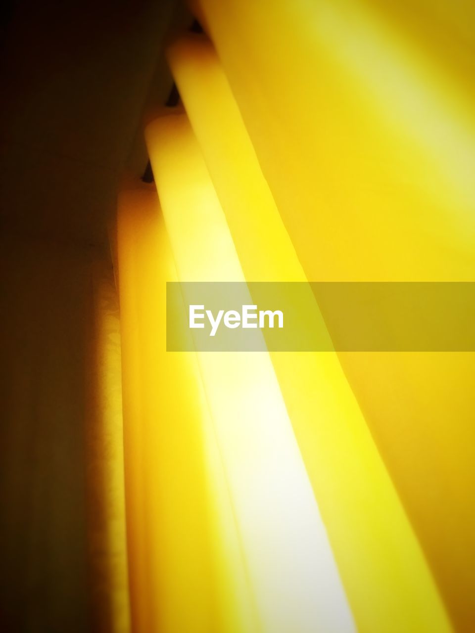 Low angle view of illuminated yellow curtain hanging at home