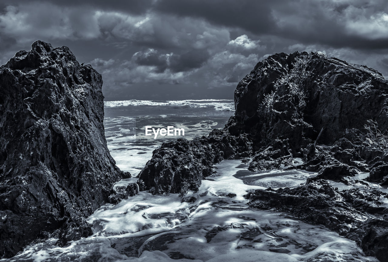 Scenic view of rocks in sea against sky