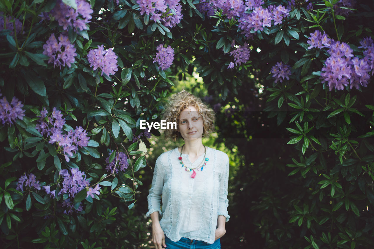 Beautiful mid adult woman standing against purple flowering plants